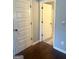Hallway with hardwood floors and view into a bathroom with beige tile floor and a light-colored vanity at 1869 Schofield Dr, Hampton, GA 30228