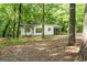 Charming single-story home with white siding nestled amongst mature trees and a natural landscape at 397 Campground Rd, Mcdonough, GA 30253