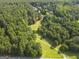 Overhead view of a green clearing with trees, tire tracks, and homes in the distance at 75 Auburn Rd, Auburn, GA 30011