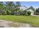 View of white home with two-car garage, green lawn and mature trees at 75 Auburn Rd, Auburn, GA 30011