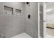 Modern shower with gray tiled walls, built-in shelving, black fixtures, and white tiled flooring at 1770 Atherton Dr, Decatur, GA 30035