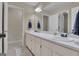 Bathroom with double sinks, vanity, and a mirror. Includes a view into the hallway at 407 Blue Smoke Trl, Peachtree City, GA 30269