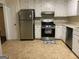 Functional kitchen equipped with stainless steel appliances, white cabinetry, and neutral tile flooring at 1725 Sara Se Ct, Conyers, GA 30013