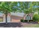 View of a brick home featuring an attached two-car garage and a well-manicured lawn with mature trees at 85 Parks Pl, Sharpsburg, GA 30277