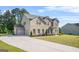Suburban home features a brick and siding exterior, a three-car garage, and a well-manicured lawn at 361 Traditions Ln, Hampton, GA 30228