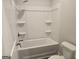 A basic bathroom features a shower-tub combo with built-in shelving and a toilet at 1676 Fuma Leaf Way # 305, Mcdonough, GA 30253