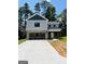 Two story home showing gray siding, brick foundation and large driveway surrounded by mature trees at 8035 Buffet Trl, Riverdale, GA 30296