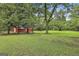 Scenic backyard with lush green lawn and mature trees, complemented by a classic red barn at 435 Jackson St, Locust Grove, GA 30248