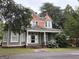 Charming two-story home with a covered porch and blooming hydrangeas set amidst lush greenery at 435 Jackson St, Locust Grove, GA 30248