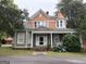 Charming two-story home featuring a quaint covered porch with blooming hydrangeas and unique architectural details at 435 Jackson St, Locust Grove, GA 30248