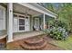 Charming front porch with white columns, brick steps, wicker furniture, and a beautiful hydrangea bush, a welcoming entry at 435 Jackson St, Locust Grove, GA 30248