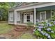 Charming front porch with white columns, brick steps, and a beautiful hydrangea bush, offering a welcoming entry at 435 Jackson St, Locust Grove, GA 30248