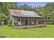 Quaint guest cottage with a rustic charm, featuring a covered porch and surrounded by lush greenery at 435 Jackson St, Locust Grove, GA 30248