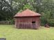 Exterior view of outbuilding with rusted metal roof; gate and equipment nearby at 435 Jackson St, Locust Grove, GA 30248