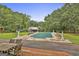 Large pool area with a covered pool, surrounded by manicured lawns, trees, and an outdoor seating area at 435 Jackson St, Locust Grove, GA 30248