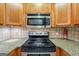 Close-up of kitchen appliances including stovetop, oven, and microwave oven with wood cabinets at 1621 White Oak Cv, Loganville, GA 30052