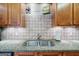 Kitchen sink and counter featuring granite countertops and tile backsplash, with wood cabinetry at 1621 White Oak Cv, Loganville, GA 30052