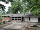 View of the backyard and back exterior of the brick and siding home, with a concrete patio and trees at 1283 Bramble Ne Rd, Atlanta, GA 30329