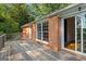 Exterior view from wooden deck reveals brick exterior with view of the lush backyard through open patio door at 315 Burke Cir, Mcdonough, GA 30253