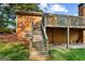 Wooden steps lead to an elevated deck, revealing a brick house with a covered patio below at 315 Burke Cir, Mcdonough, GA 30253
