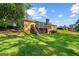 Expansive backyard with lush green lawn, a deck, and mature trees surrounding the brick house at 315 Burke Cir, Mcdonough, GA 30253