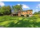 Lush green backyard with a brick home, wooden deck, and mature trees surrounding the lawn at 315 Burke Cir, Mcdonough, GA 30253