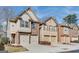 View of the brick exterior of townhomes featuring attached garages and professionally maintained landscaping at 180 Oakland Hills Way, Lawrenceville, GA 30044