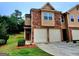 Charming townhome with a two-car garage, brick accents, and well-maintained landscaping in a residential neighborhood at 180 Oakland Hills Way, Lawrenceville, GA 30044