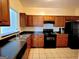 Functional kitchen with wood cabinets, black appliances, a double sink, and tile flooring at 180 Oakland Hills Way, Lawrenceville, GA 30044