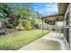 Large, lush backyard featuring a covered patio, green grass, and a wooded area in the background at 230 Haleys Ct, Woodstock, GA 30188