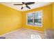 This bright yellow bedroom features a ceiling fan and a large window offering plenty of natural light at 230 Haleys Ct, Woodstock, GA 30188