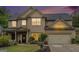 Charming two-story home with a well-manicured lawn, beautiful landscaping and a two car garage at dusk at 230 Haleys Ct, Woodstock, GA 30188