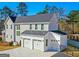 View of attached three car garage featuring white garage doors, siding and black gutters at 915 Laurel Brooke Ave, Peachtree City, GA 30269