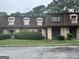 View of a townhouse-style home featuring dormer windows, grass, and a paved parking area in front at 2968 Par Lorraine, Lithonia, GA 30038