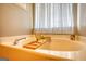 Bright bathroom features a soaking tub with a bamboo tray and a sheer curtained window at 50 Berkshire Pass, Covington, GA 30016