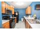 A functional kitchen featuring a black fridge, stove, oak cabinets and a modern sink at 1346 Revelstoke Cv, Riverdale, GA 30296