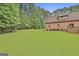 Expansive lawn space behind a brick home with mature trees and manicured lawn at 210 Short Rd, Sharpsburg, GA 30277