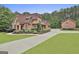 Stately brick home boasts manicured landscaping, a circular driveway, and mature trees at 210 Short Rd, Sharpsburg, GA 30277