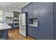 Well-lit kitchen featuring custom blue cabinets, stainless steel appliances, and gleaming hardwood floors at 210 Short Rd, Sharpsburg, GA 30277