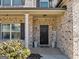 Inviting front porch with brick facade, dark door, and potted plants, creates a welcoming entrance at 10736 Southwood Dr, Hampton, GA 30228
