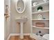 Charming powder room with pedestal sink, oval mirror, and built-in shelving for storage and decor at 500 Merrill Ln, Peachtree City, GA 30269