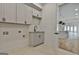 Laundry room with gray cabinets and a sink opens to a kitchen with pendant lights and marble counters at 1240 Hayes Sq, Peachtree City, GA 30269