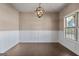 A bright dining room with wainscoting, hardwood floors, a modern chandelier, and a large window at 475 Louise Way, Locust Grove, GA 30248