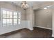 A bright dining room with wainscoting, hardwood floors, a modern chandelier, and a large window at 475 Louise Way, Locust Grove, GA 30248