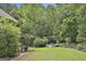 Serene backyard featuring a fire pit area and lush greenery with wooded backdrop at 135 Rockglen Ct, Fayetteville, GA 30215