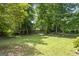 Large, green backyard surrounded by mature trees and lush greenery, offering privacy and space for outdoor activities at 23 Hunting Creek Dr, Marietta, GA 30068