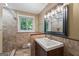 Bathroom with decorative vanity and shower/tub surrounded by natural stone and a window providing natural light at 23 Hunting Creek Dr, Marietta, GA 30068