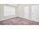 Bright bedroom with plush carpeting, window with blinds, and access to closets at 9046 Holder Rd, Locust Grove, GA 30248
