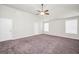 Spacious carpeted bedroom featuring a ceiling fan, two windows and two doors at 9046 Holder Rd, Locust Grove, GA 30248