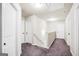 Upstairs hallway with neutral paint, purple carpet, white doors, and simple railing at 9046 Holder Rd, Locust Grove, GA 30248
